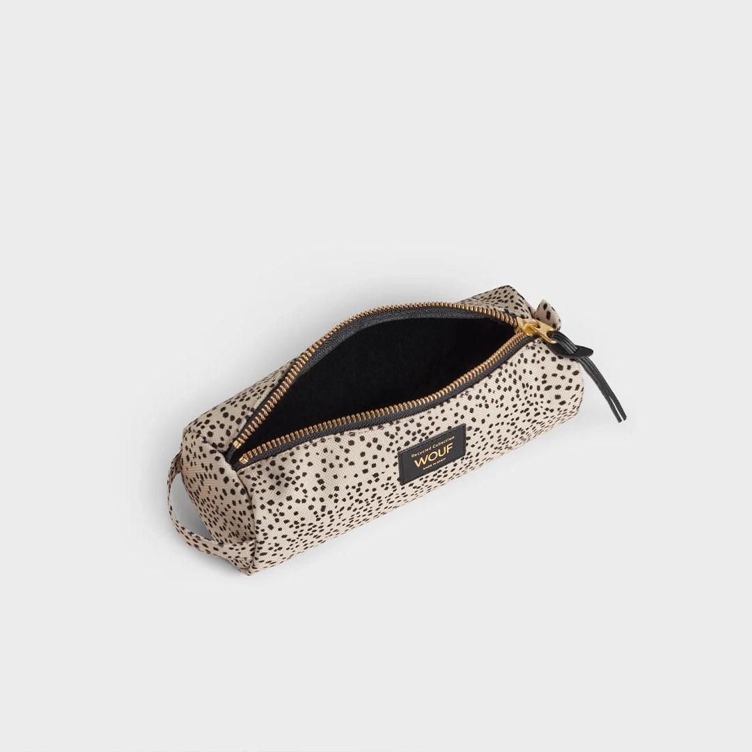Vue en angle de la trousse WOUF avec la fermeture éclair partiellement ouverte, révélant l'intérieur noir et l'imprimé à pois marron sur fond beige