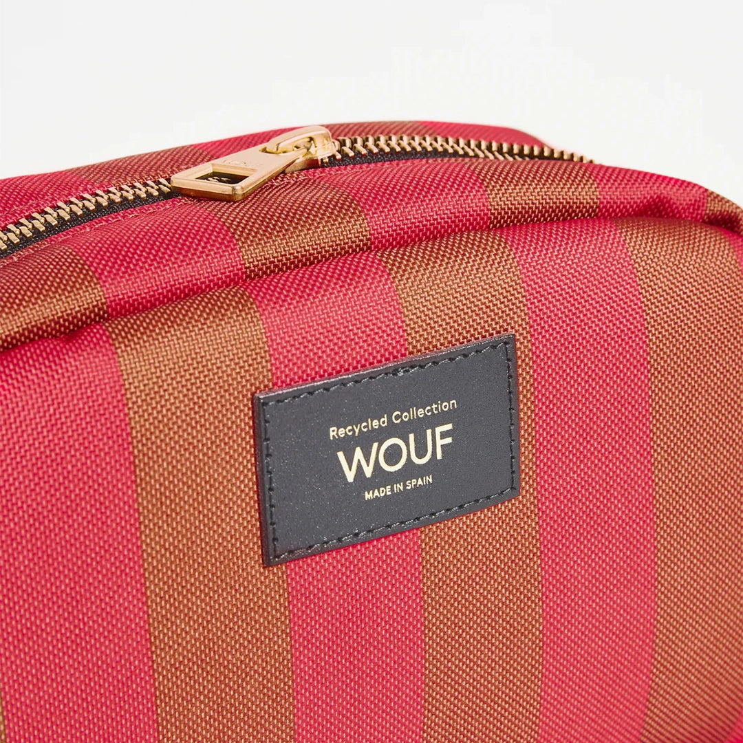 Gros plan sur la fermeture éclair en or de la trousse de toilette Pat de Wouf, montrant l'étiquette en cuir recyclé avec le logo Wouf